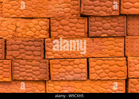 background - stack of textured bricks made of red clay Stock Photo