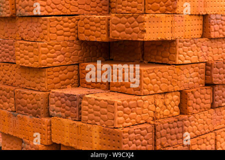 background - stack of textured bricks made of red clay Stock Photo