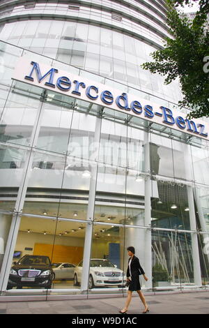 A woman walks by a dealership of Mercedes-Benz luxury sedans wait for ...