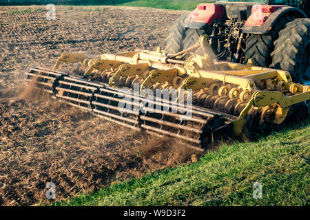 tractor cultivator plows the land, prepares for crops. dust on field Stock Photo