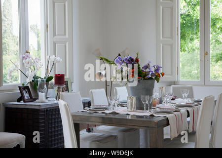 Interior with an elegant dining room and table set in a home facing a garden, in Italy Stock Photo
