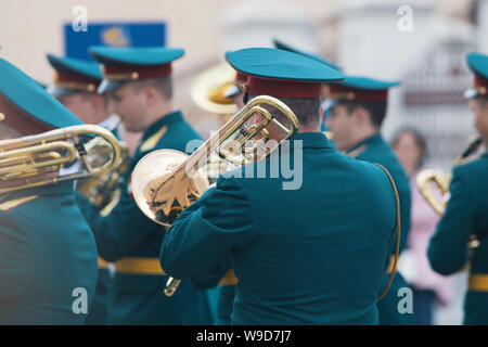 A wind instrument parade - man in green costumes holding a trumpet and playing it Stock Photo