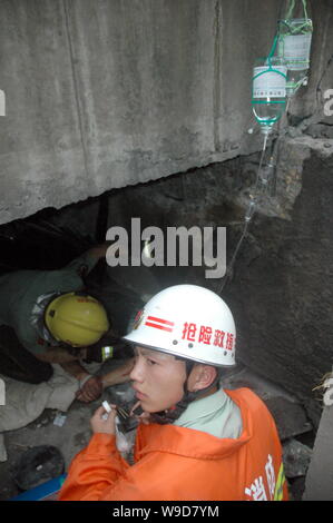 Chinese rescuers infuse physiological saline solution into a man being buried in the rubble after a viaduct collapsed in Zhuzhou city, central Chinas Stock Photo