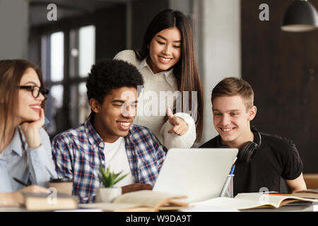 College students using laptop in library, studying together Stock Photo