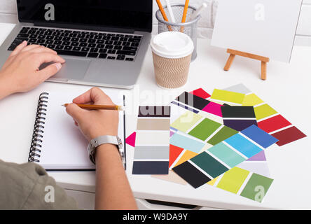 Woman writing in notebook and typing on laptop Stock Photo