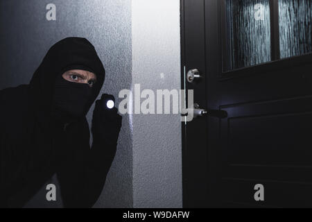 burglar in mask ready to break in the house at night Stock Photo