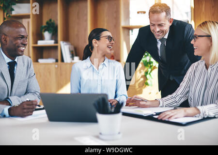 Laughing group of diverse businesspeople having a meeting together at a boardroom table in an office Stock Photo