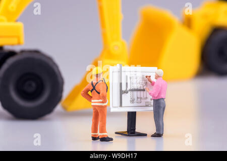 Miniature engineering people and architecture working on construction drawing. Elegant Design for industrial and construction concept. Stock Photo