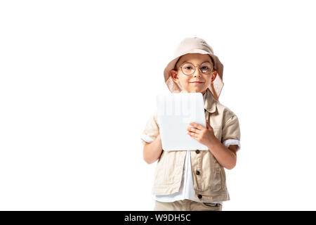 front view of cheerful explorer child in glasses and hat holding digital tablet isolated on white Stock Photo
