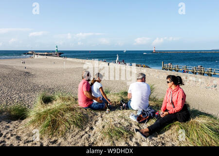 Family beach people enjoying a sunny day in the sand dunes overlooking the beach in Warnemunde dunes Germany Stock Photo