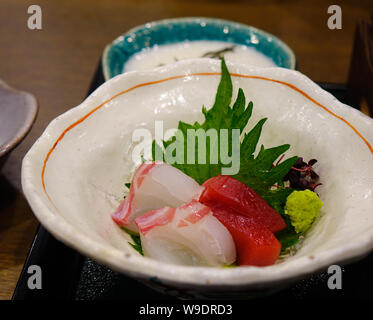 Mixed sliced fish sashimi on ice in the bowl at traditional Japanese restaurant. Stock Photo