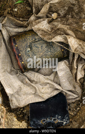 Vintage chest deployed from a tissue bundle excavated from the ground, and trenching tool in pit Stock Photo