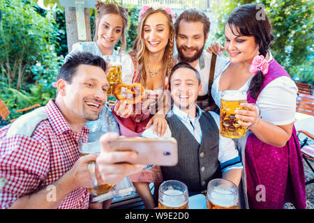 Cheerful group of friends taking a selfie in Bavarian beer garden Stock Photo