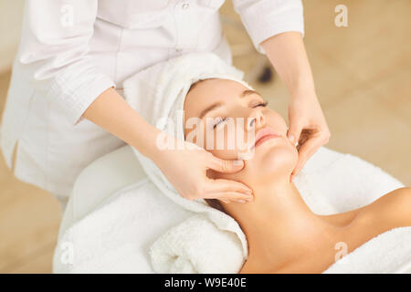Beautician makes facial massage to the girl Stock Photo