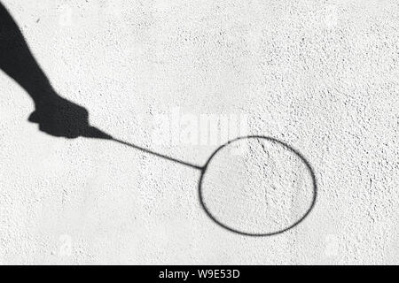 Shadow of a badminton racket on a white wall. Sports concept. Banbinton racket in the hand. Creative copyspace Stock Photo