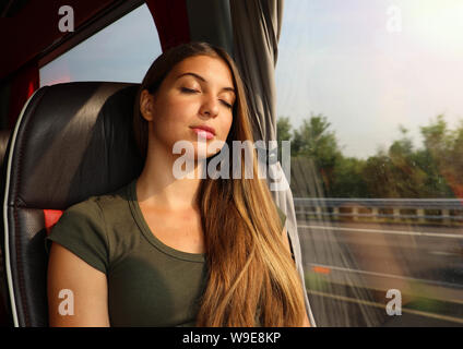 Young beautiful woman sleeping sitting in the bus. Bus passenger traveling sitting in a seat and sleeping. Stock Photo