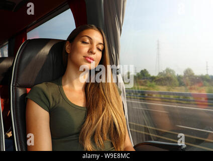 Young beautiful woman sleeping sitting in the bus. Bus passenger traveling sitting in a seat and sleeping. Stock Photo