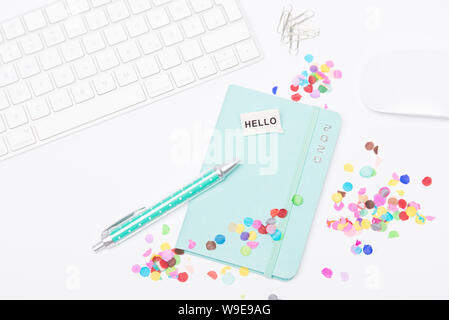Desk with colorful confetti, keyboard and mouse, calendar 2020 and a ballpoint pen Stock Photo