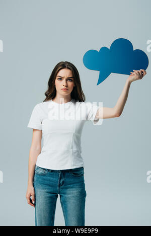 sad beautiful girl in white t-shirt holding blank blue speech bubble isolated on grey Stock Photo