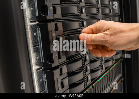 Male IT Engineer Replacing Server Drive in SAN At Datacenter Stock Photo