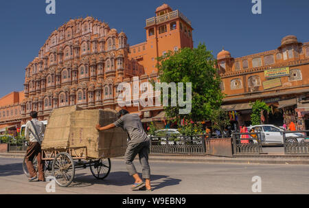 Jaipur, Rajastan, India - April 1, 2018: Two men pushing a wagon in front of the Palace of the Winds in Jaipur Stock Photo