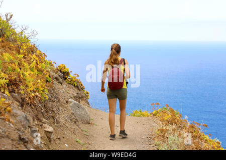 Young hiker woman walking on a trail overlooking the sea in Tenerife Stock Photo