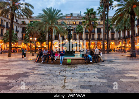 Evening at Placa Reial square in city of Barcelona in Catalonia, Spain, people relax by the Fountain of the Three Graces in Gothic Quarter - Barri Got Stock Photo