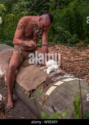 Wampanoag man making jewlery by drilling a hole. Stock Photo