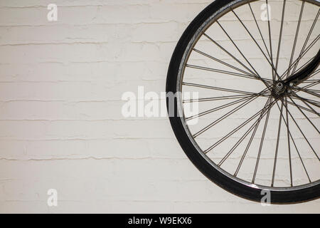 Black bicycle wheel against white brick painted wall Stock Photo