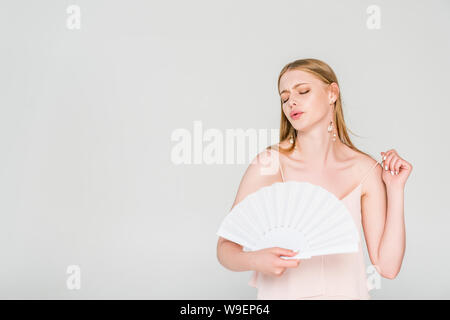 beautiful young woman with hand fan suffering from heat isolated on grey Stock Photo