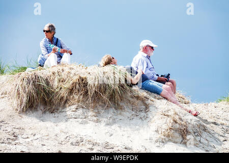 People relax in the dunes and watch the sea, the beach in Warnemunde Rostock Germany Stock Photo