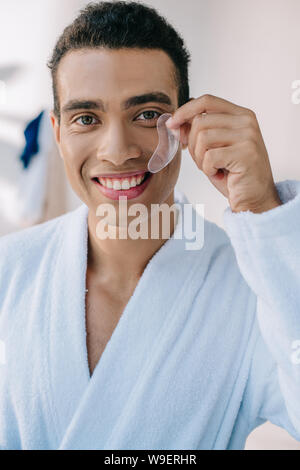 handsome young man in bathrobe showing patch and smiling while looking at camera Stock Photo