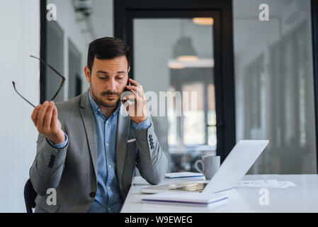 Stressed out businessman in office making important phone call about serious problem working under pressure and tight deadline Stock Photo