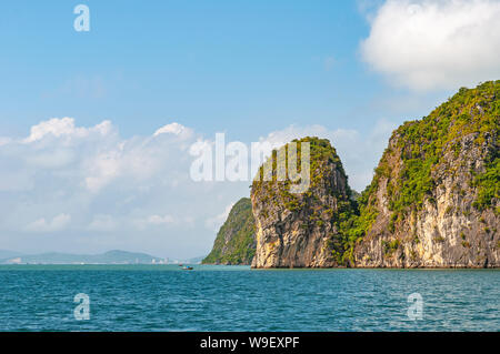 The geologic karst rock formations of Halong Bay in the South China Sea with the skyline of Haiphong city in the background, North Vietnam. Stock Photo