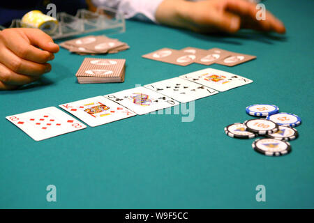 On the poker table there is a combination of cards, tokens, croupier hands, a stack for tokens. Stock Photo