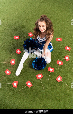 High school senior girl holding pom poms and wearing cheerleader outfit  lying on grass in Sacramento