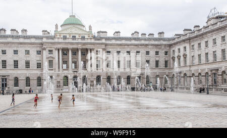 London, England - May 2019: Kids playing with water fountains in the courtyard of Somerset House, London UK Stock Photo