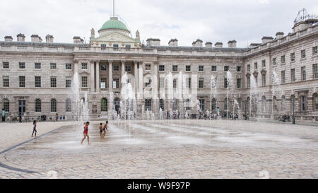 London, England - May 2019: Kids playing with water fountains in the courtyard of Somerset House, London UK Stock Photo