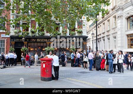 Crowds enjoying a summers evening drink outside The Sherlock Holmes  public house on Northumberland Street, Central London England UK Stock Photo