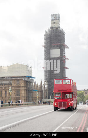 A vintage heritage red London bus with a scaffolding covered Big Ben / Elizabeth tower at the background Stock Photo