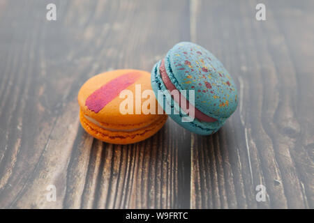 Multi-colored macaroons on a wooden table. Orange and blue macaroon. Stock Photo