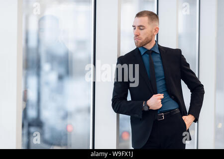 Portrait of young confident stylish business man with crossed hands near window. Stock Photo