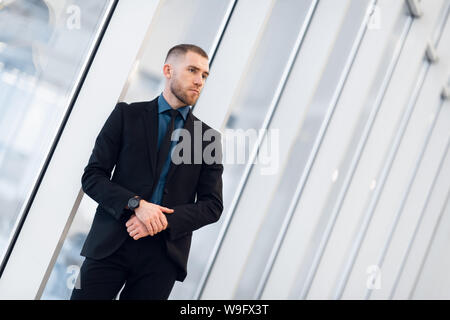Portrait of young confident stylish business man with crossed hands near window. Stock Photo