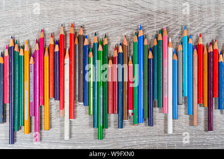 some old colored pencils lined up on a wooden table Stock Photo