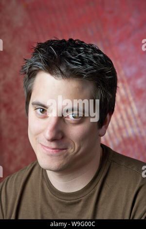 Portrait of a young Caucasian man smiling wearing a T-shirt on a red background Stock Photo