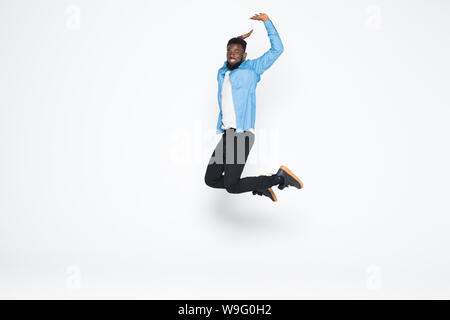 Full length portrait of handsome joyful afro man wearing casual denim jeans clothing jumping up, isolated on gray background Stock Photo