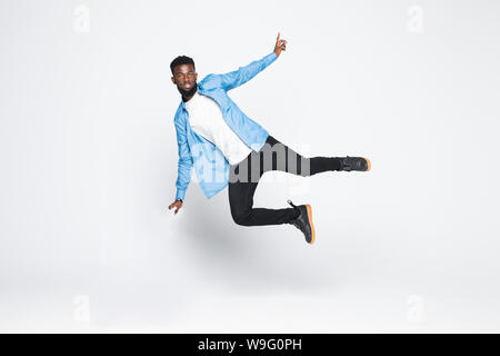 Full length portrait of handsome joyful afro man wearing casual denim jeans clothing jumping up, isolated on gray background Stock Photo