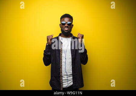 Young african american man on vibrant yellow background celebrating a victory Stock Photo