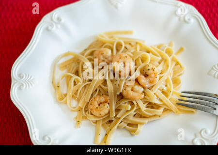 Shrimp scampi a garlic seasoned shrimp in butter, served on fettuccine  pasta. White plate, closeup. USA. Stock Photo