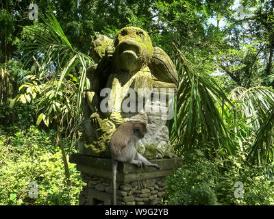 low angle shot of a long-tailed macaque on a monkey statue in bali Stock Photo